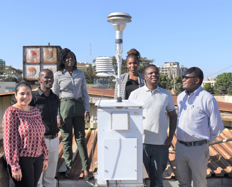 Six people standing  next to a rooftop air quality monitor