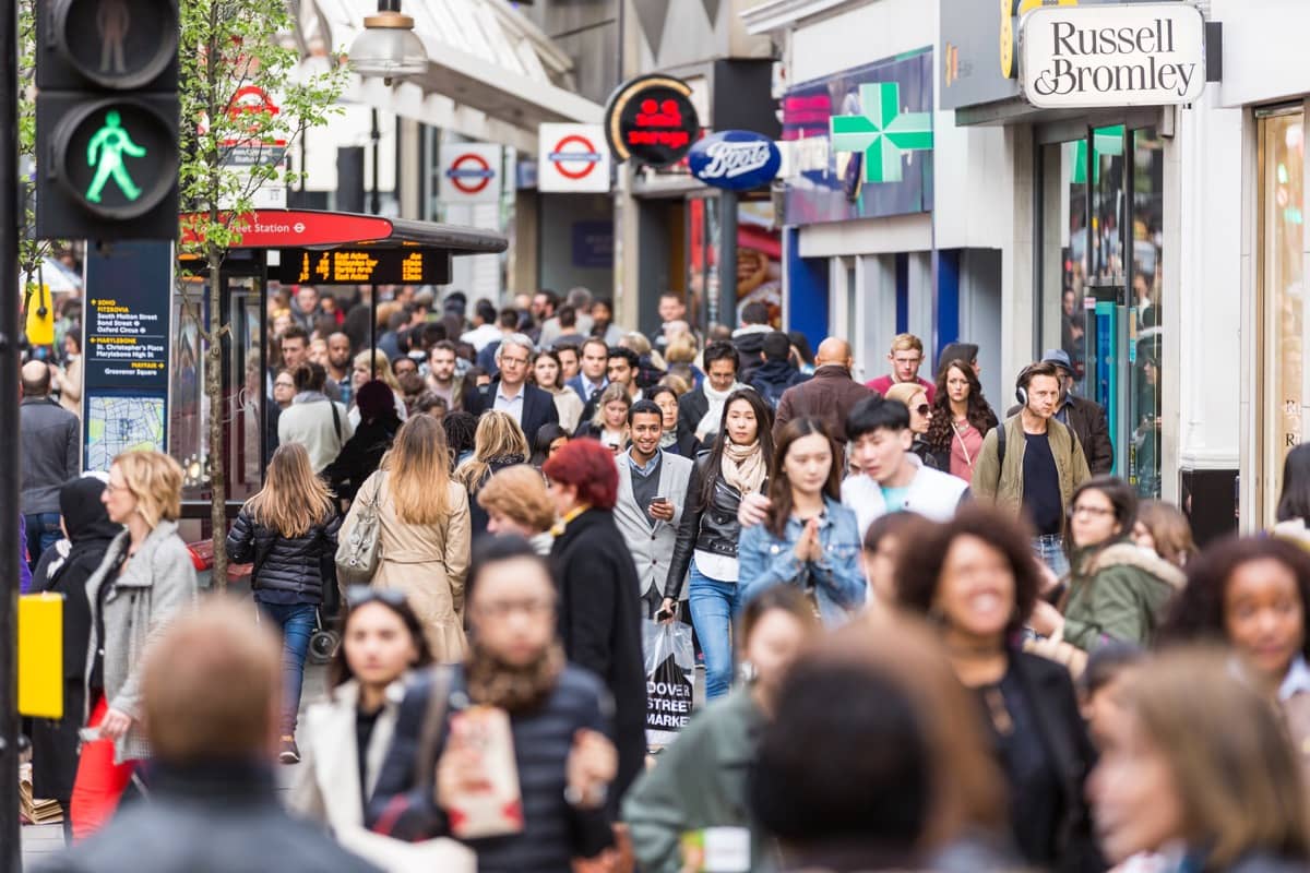 Pedestrians crowded together on a broad sidewalk