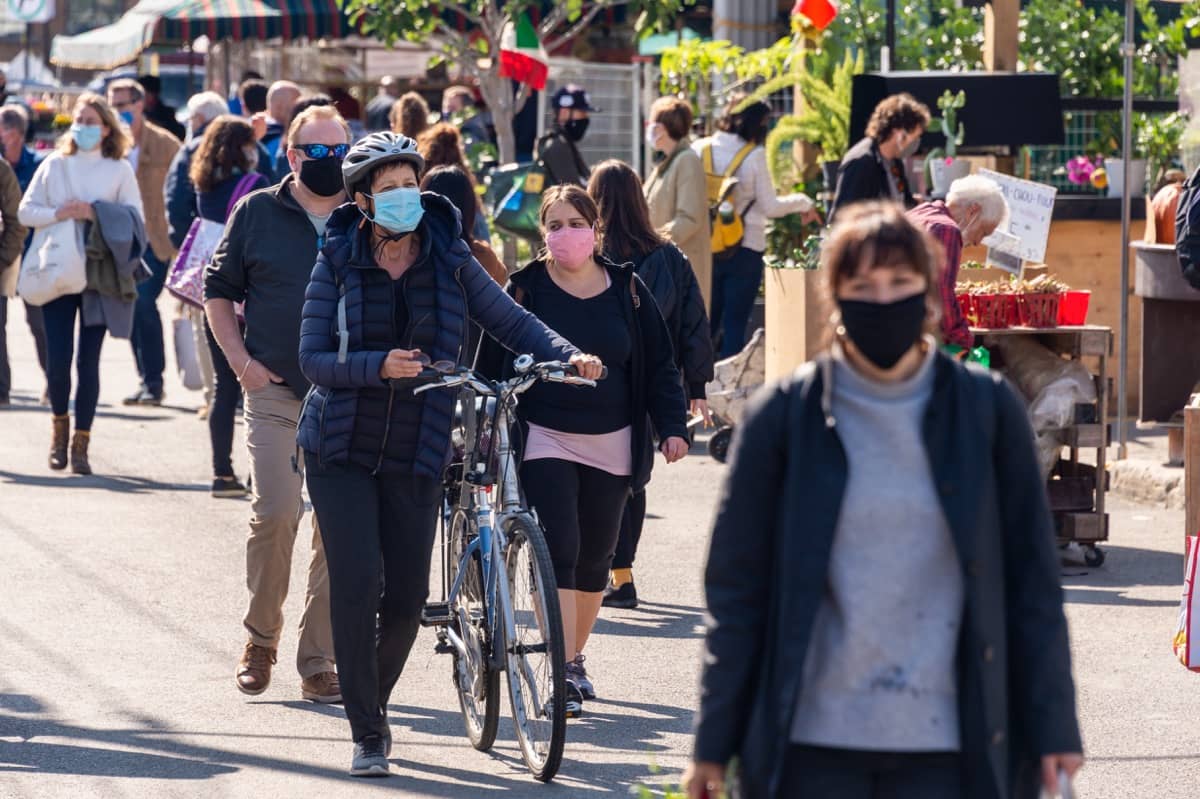 Masked pedestrians walking on a broad sidewalk