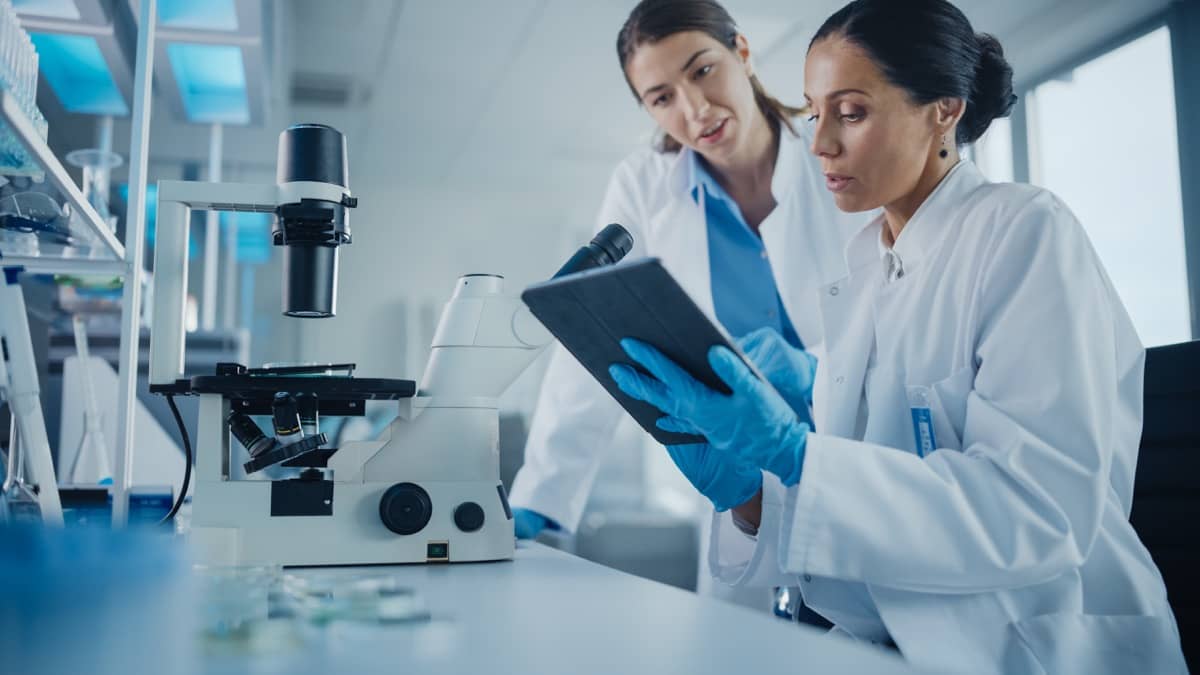 Two scientists working in a lab wearing lab coats